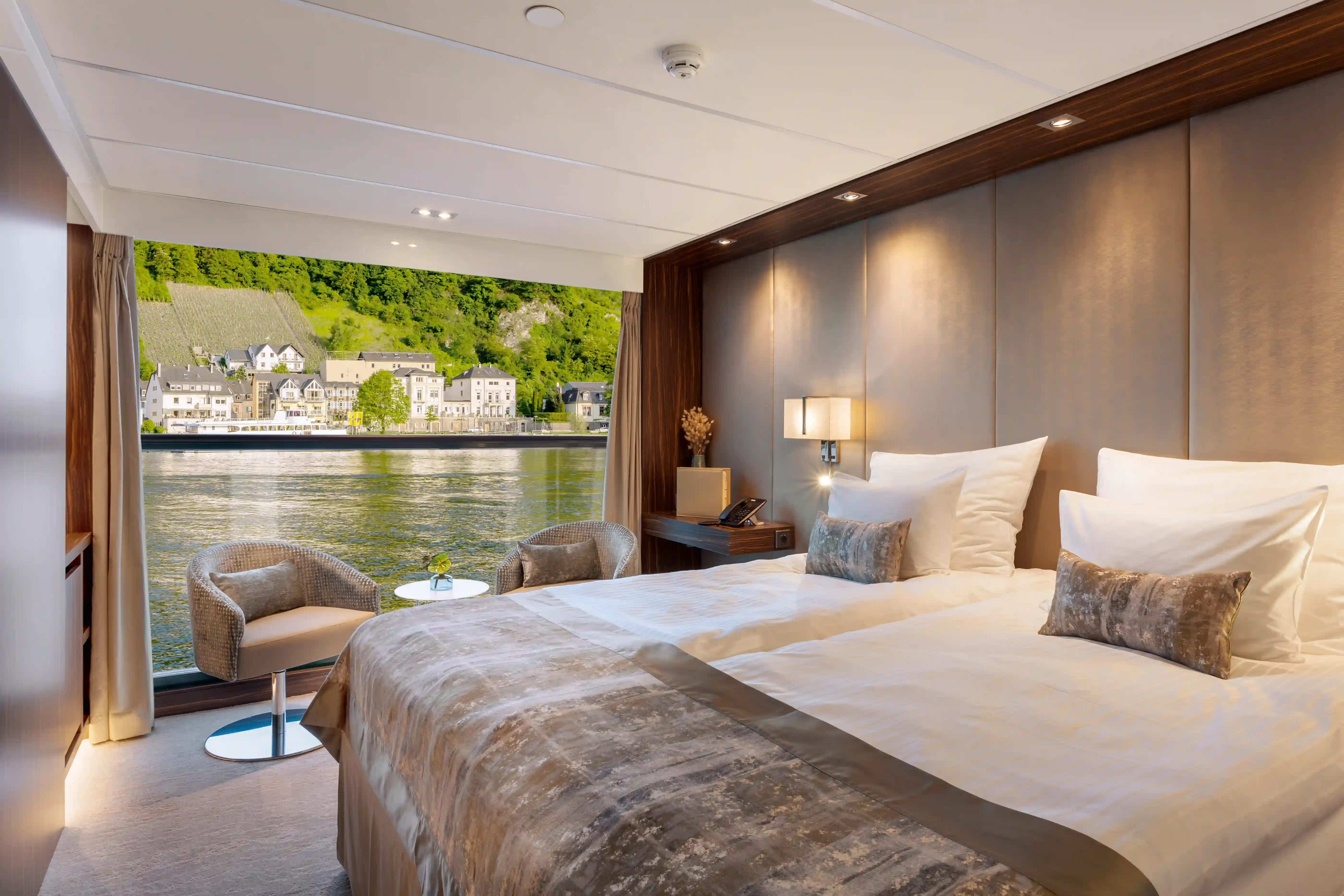 Komfortable Kabine mit Doppelbett, Sitzbereich und Panoramafenster mit Flussblick