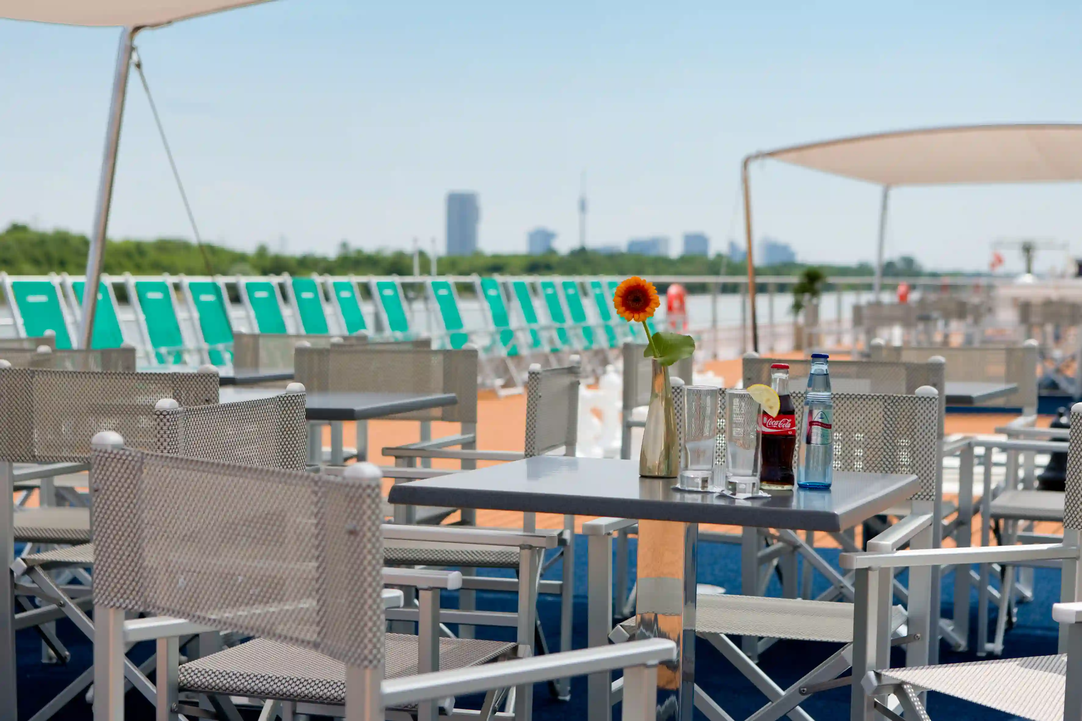 Sonnendeck mit Tischen, Stühlen und Blick auf den Fluss