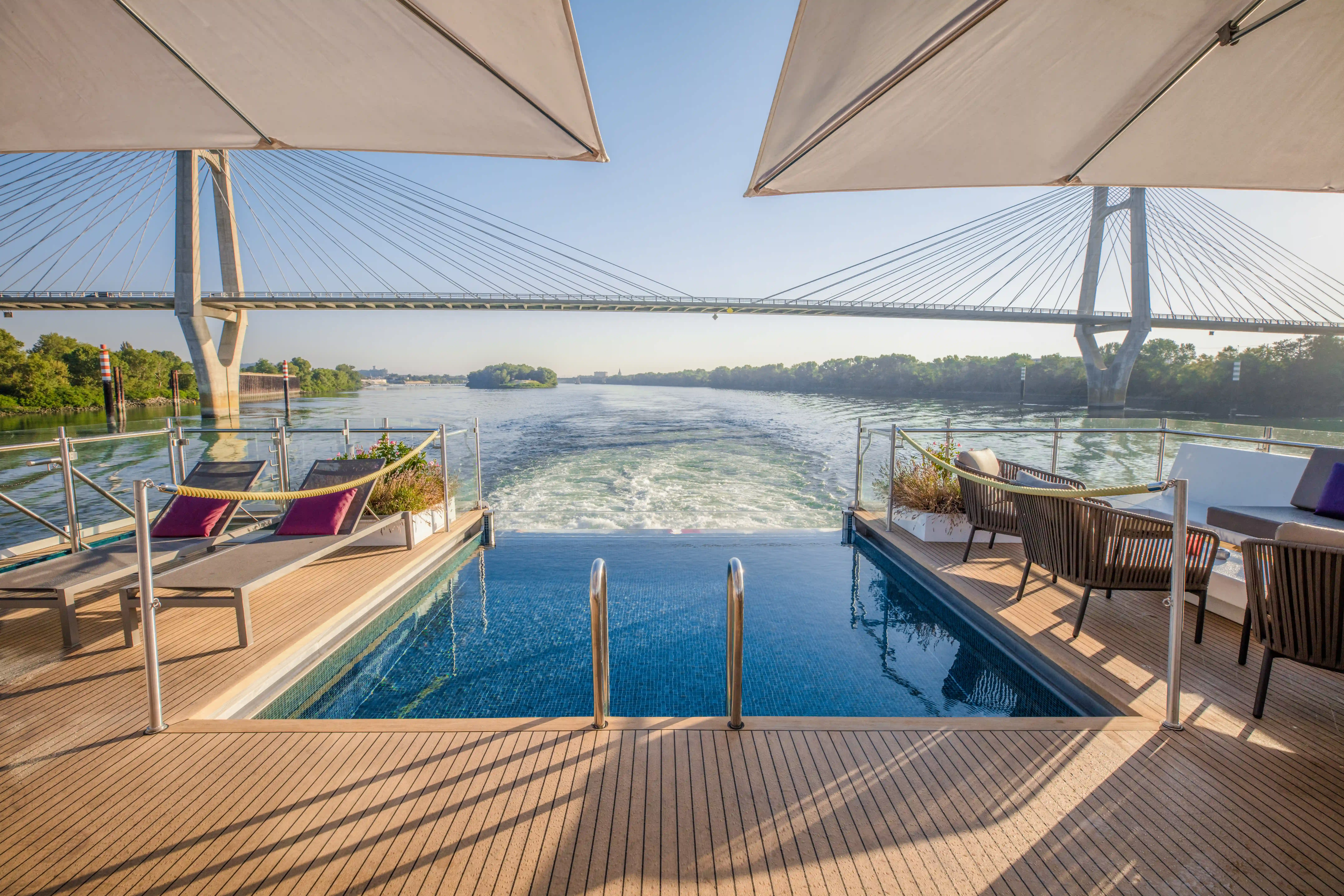 Eleganter Infinity-Pool auf dem Sonnendeck mit Blick auf den Fluss und die vorbeiziehende Landschaft