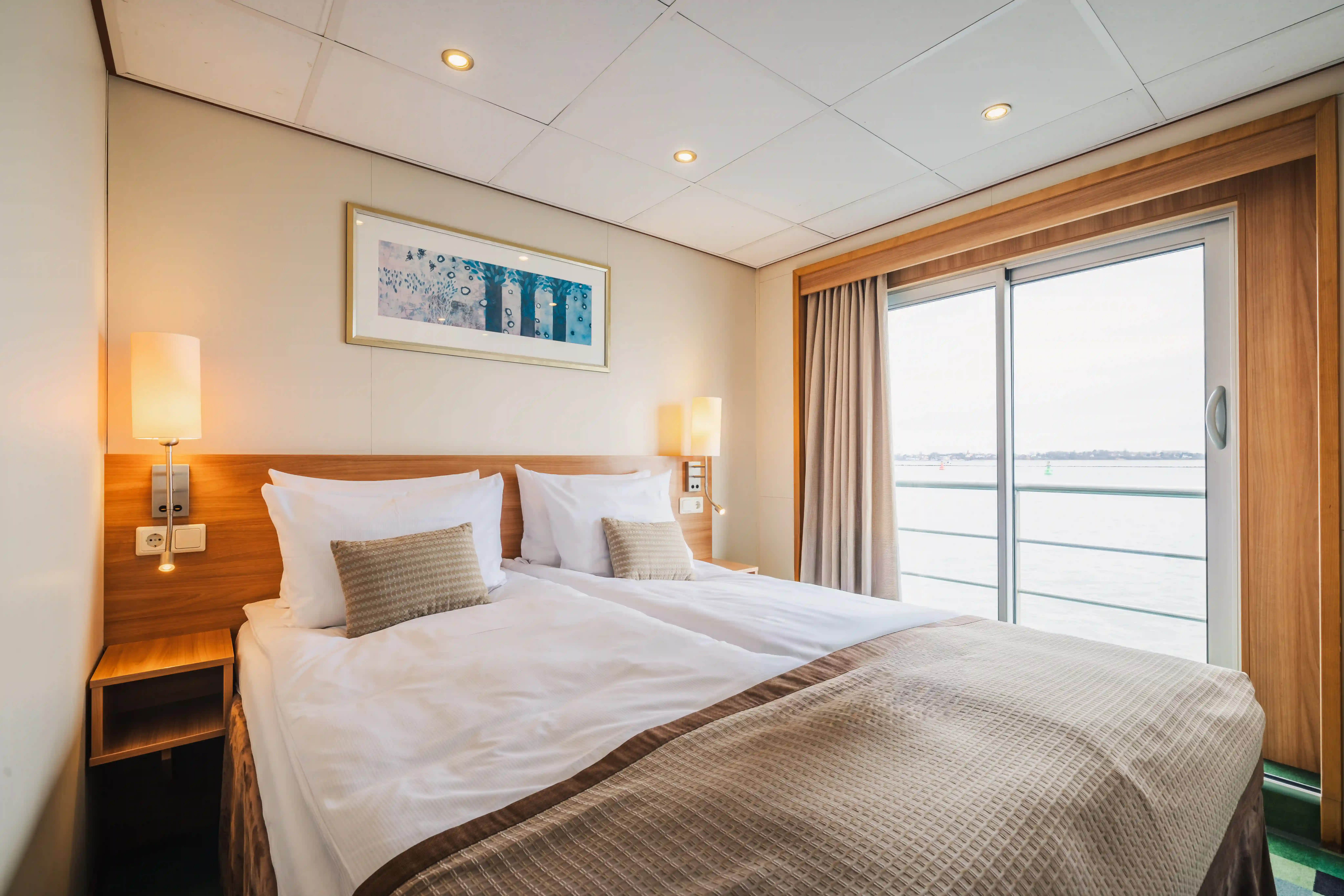 Helle Suite mit Doppelbett und großem Balkonfenster mit Blick auf den Fluss
