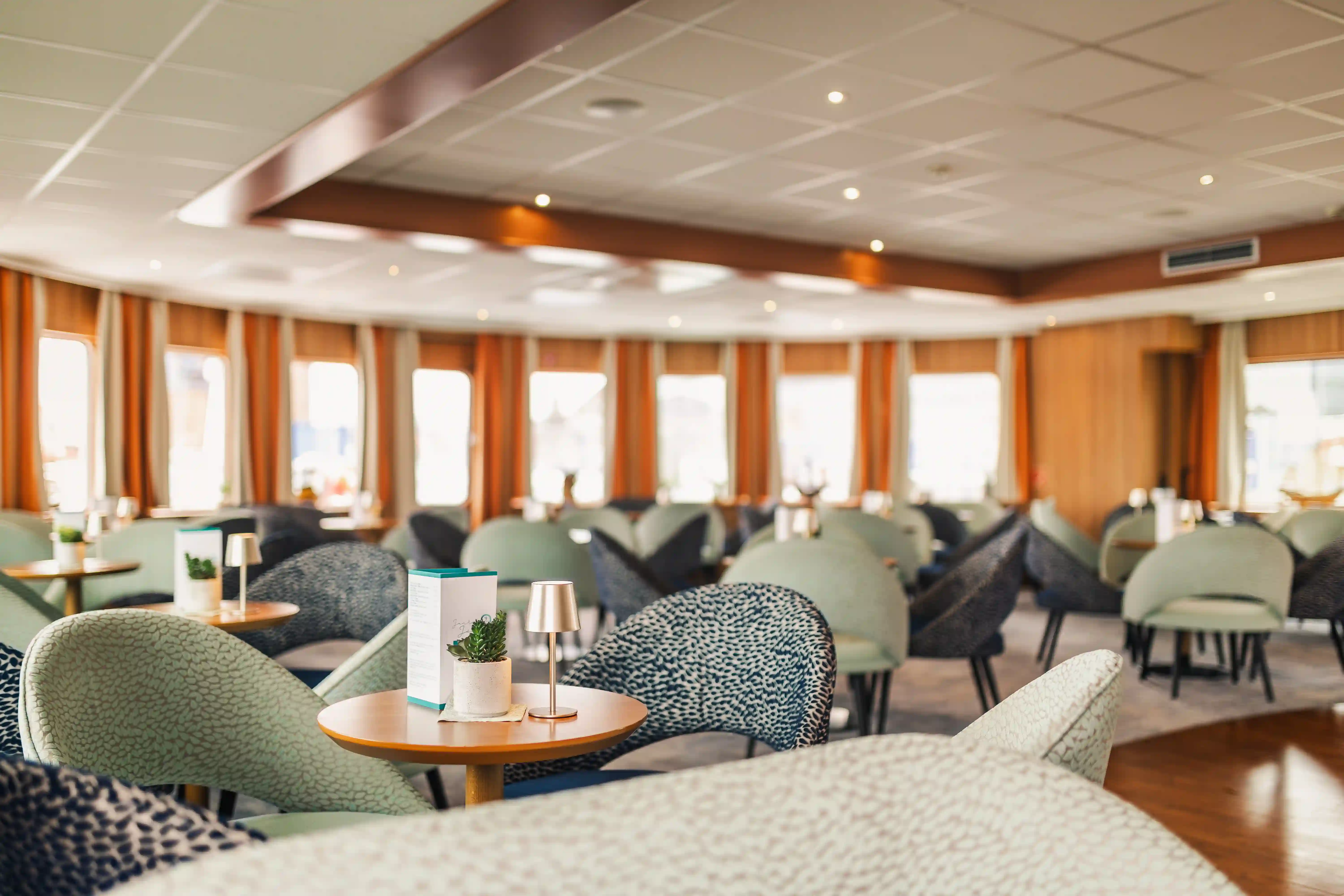Elegante Panorama-Lounge mit Sesseln und Tischen für entspannte Stunden an Bord