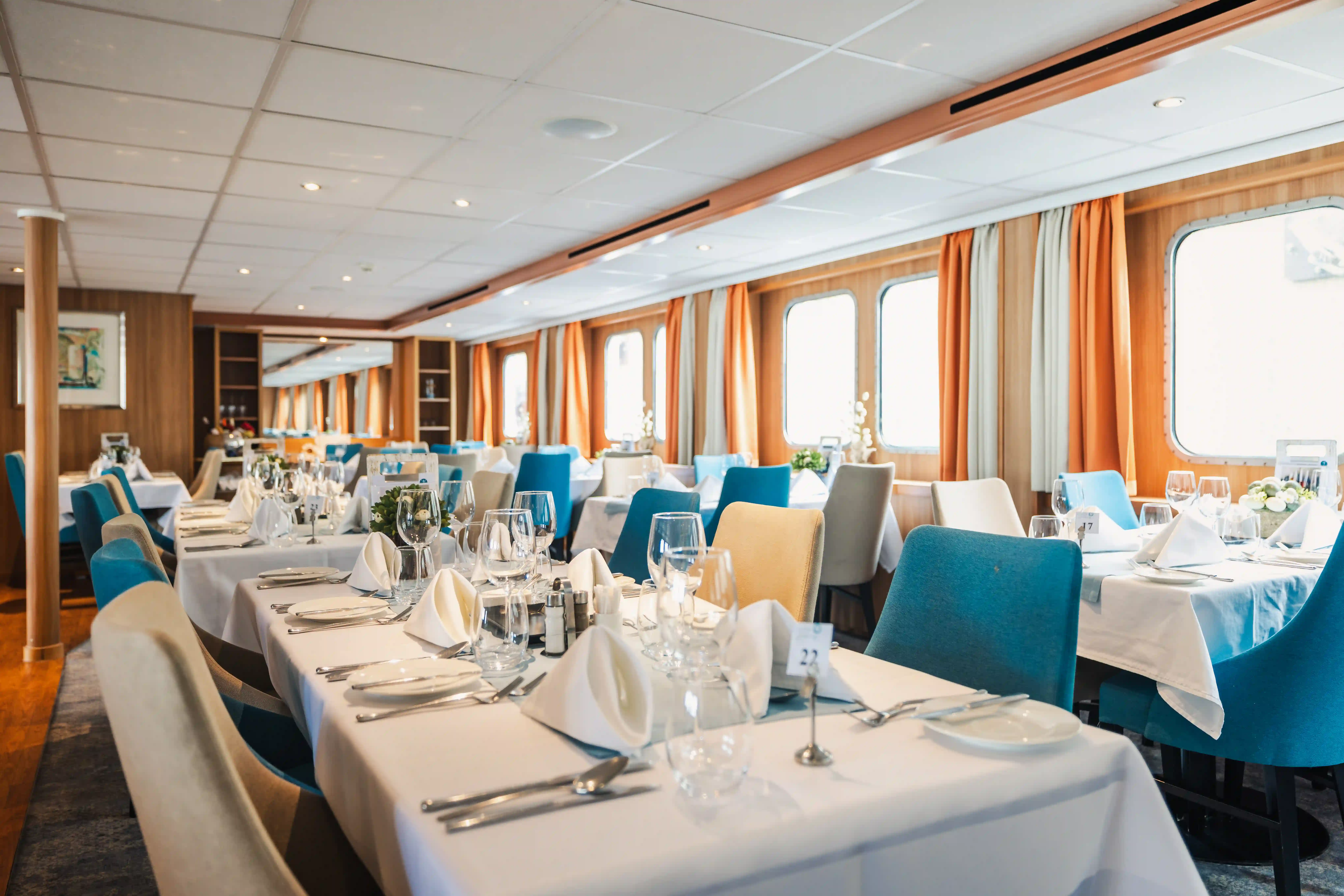 Stilvoll eingerichtetes Bordrestaurant mit gedeckten Tischen und großen Panoramafenstern