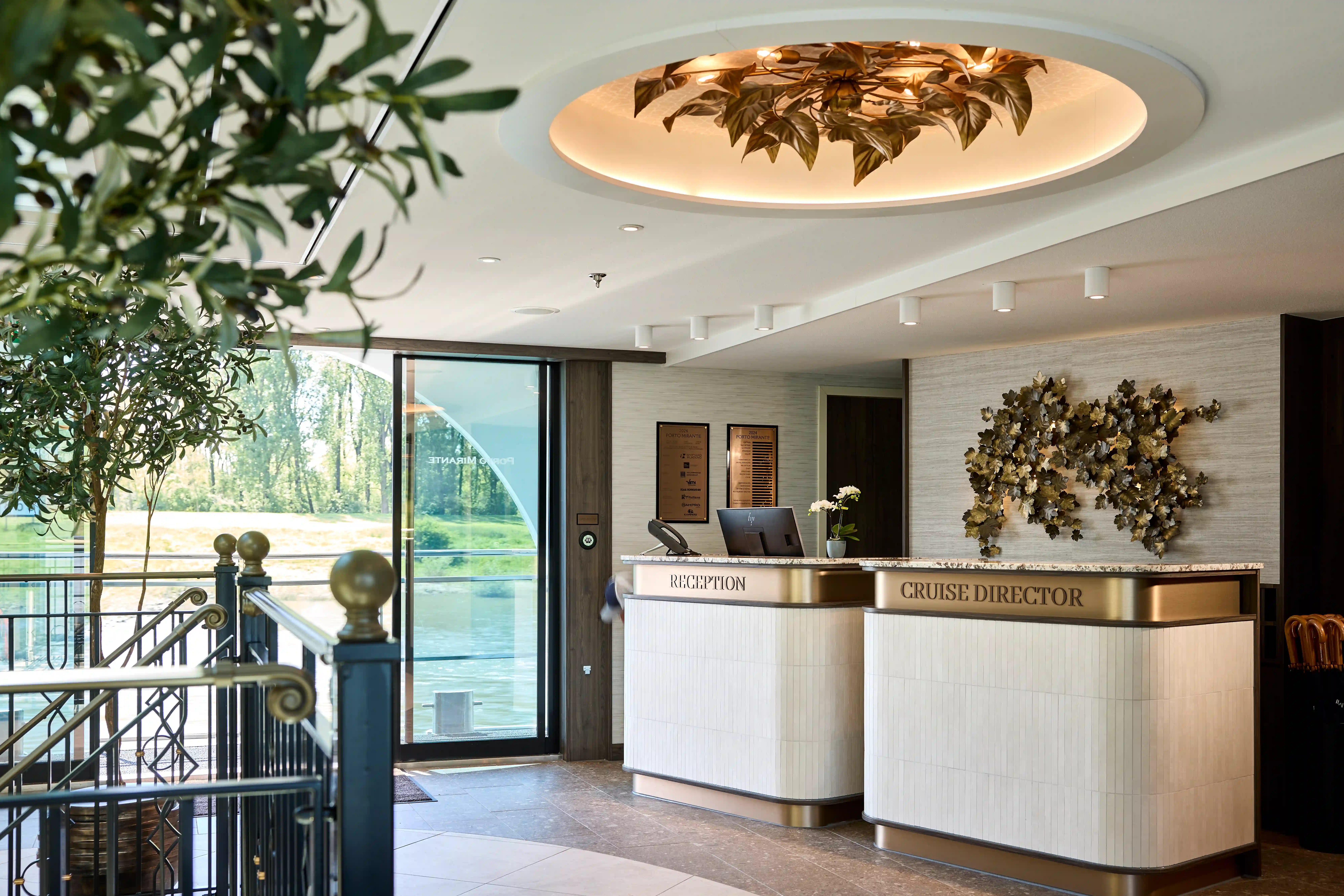 Moderne Rezeption an Bord eines Flussschiffes mit Empfangstresen, dekorativer Beleuchtung und Blick nach aussen.