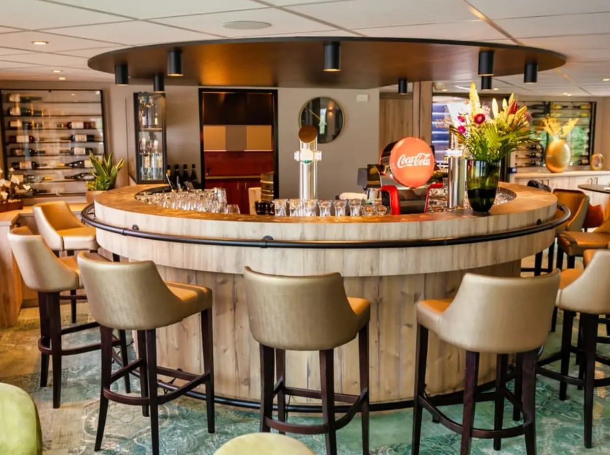 Runde Bar mit Holzverkleidung, Barhockern, Gläsern, Zapfanlage und moderner Beleuchtung