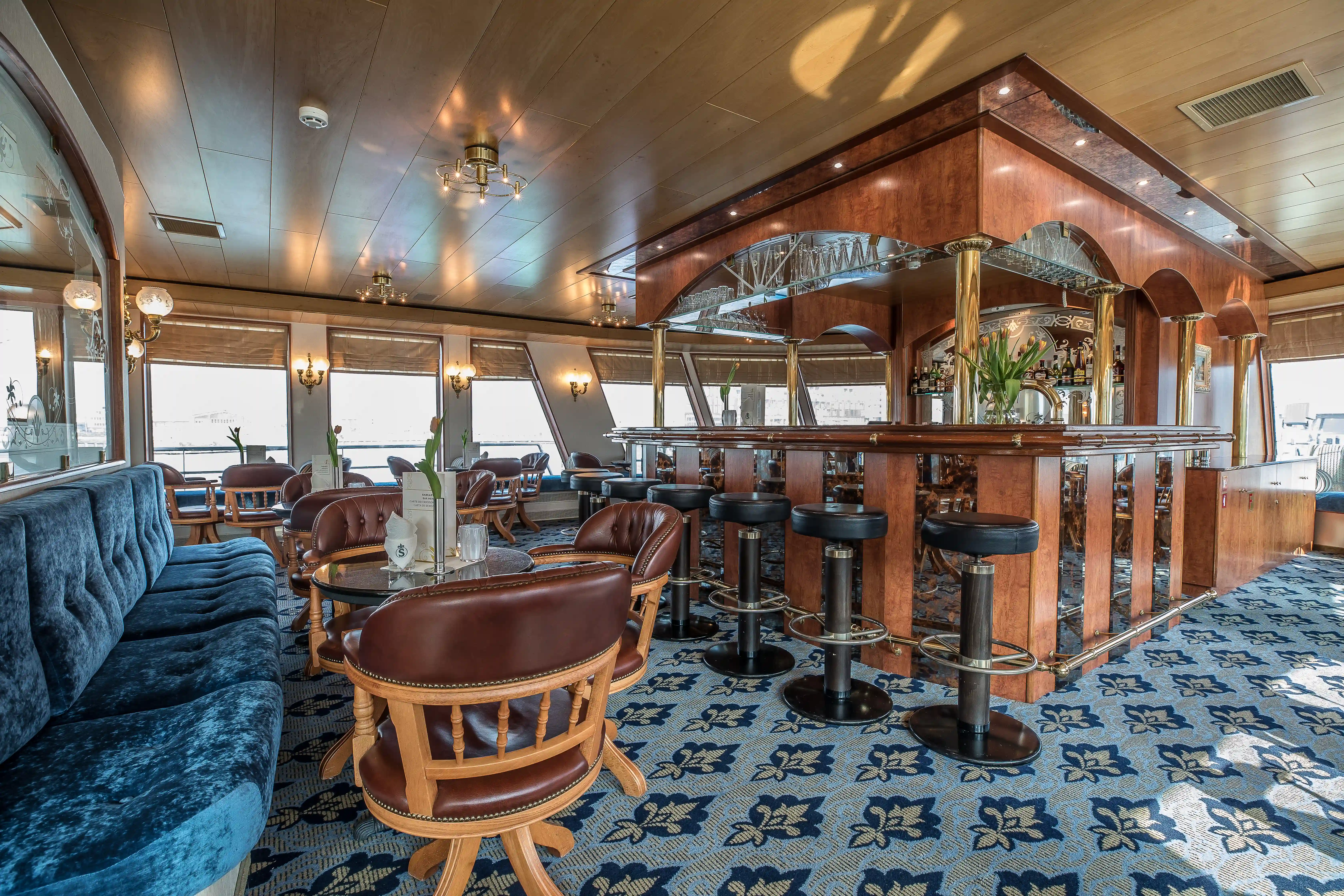 Klassische Schiffsbar mit Holzverkleidung, gepolsterten Sitzgelegenheiten und dekorativen Spiegeln