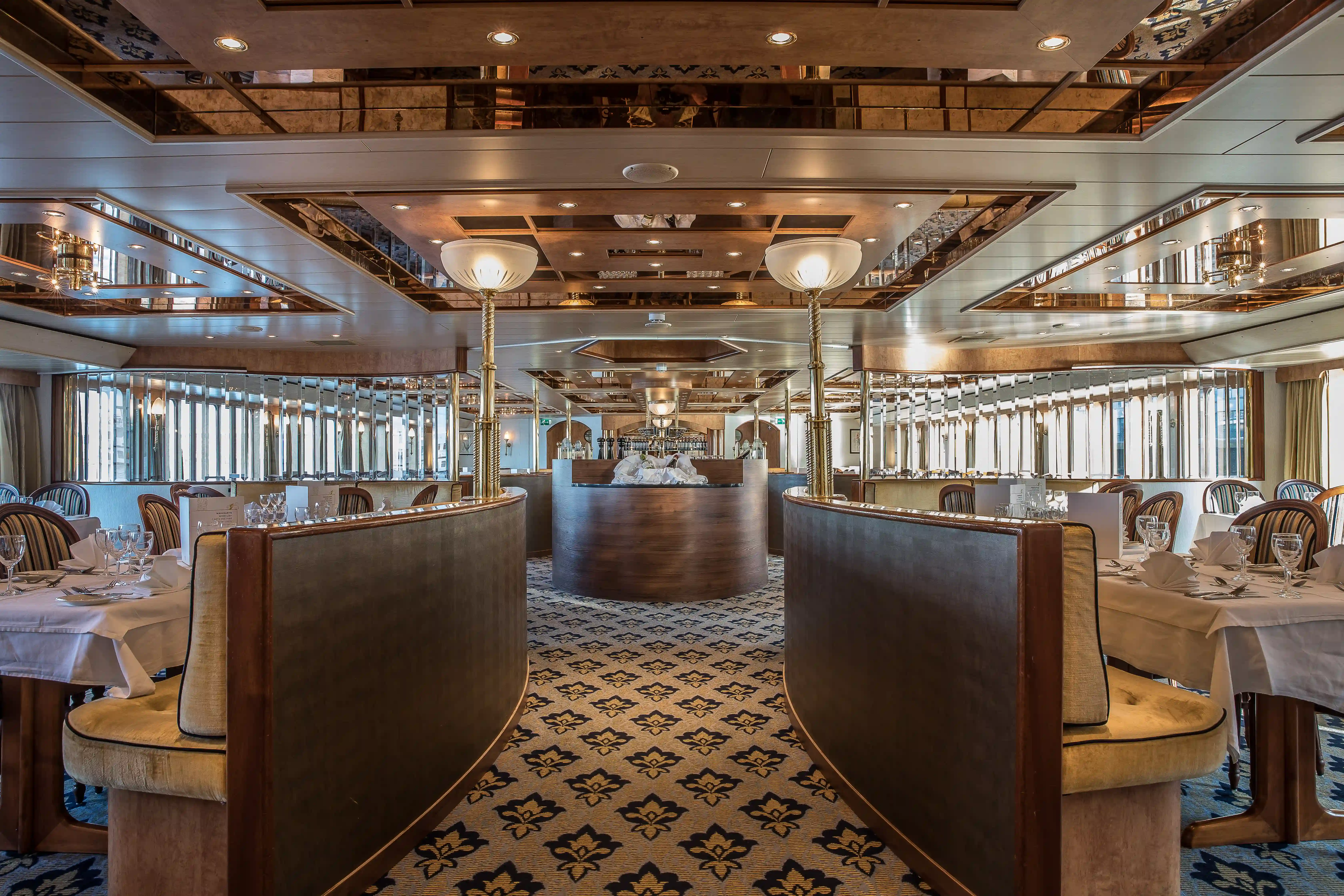 Restaurantbereich mit gedeckten Tischen, gepolsterten Sitzbänken, Spiegeldecke und heller Atmosphäre