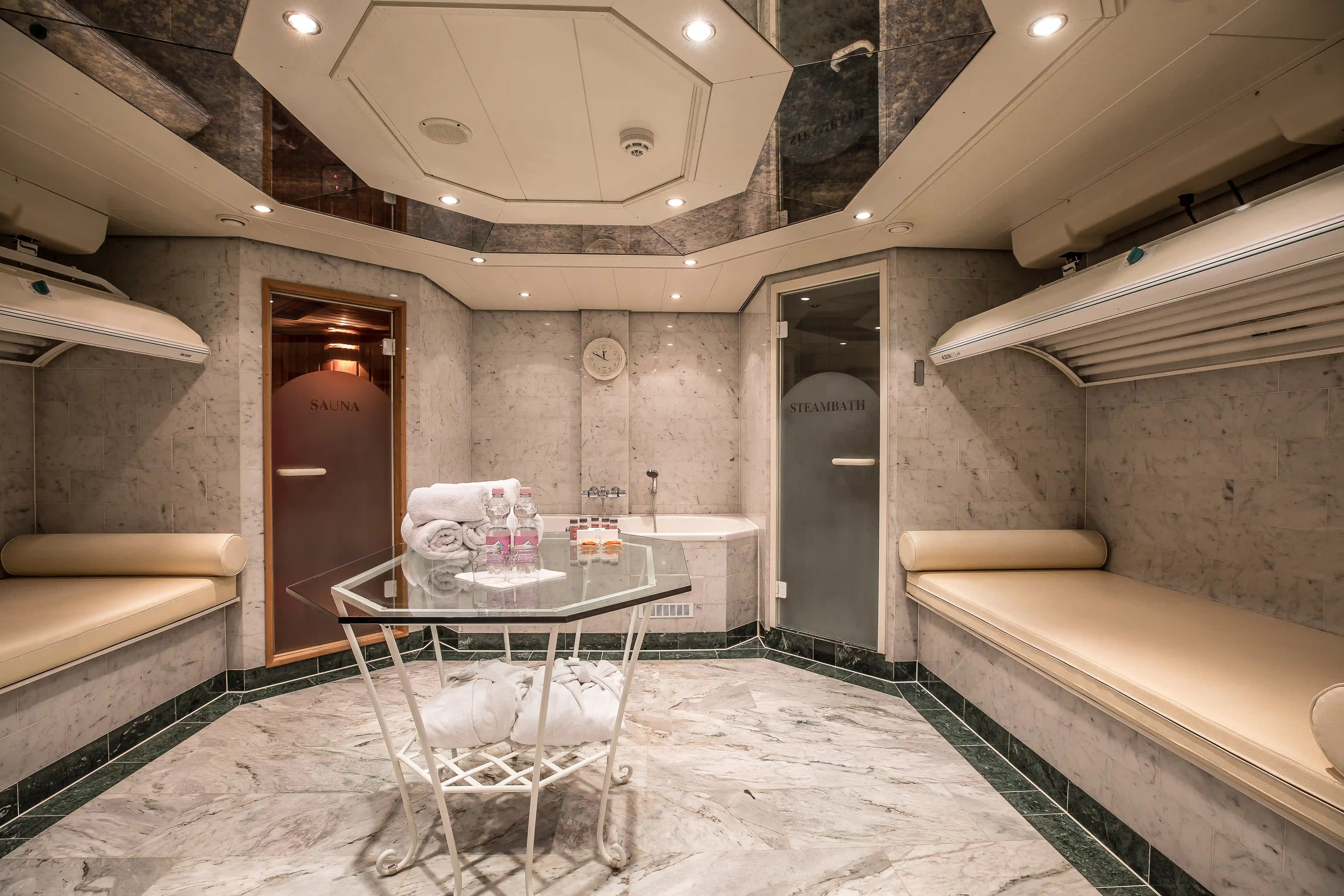 Wellnessbereich mit Sauna, Dampfbad, Liegen, Marmorboden, Handtüchern und ruhiger Beleuchtung