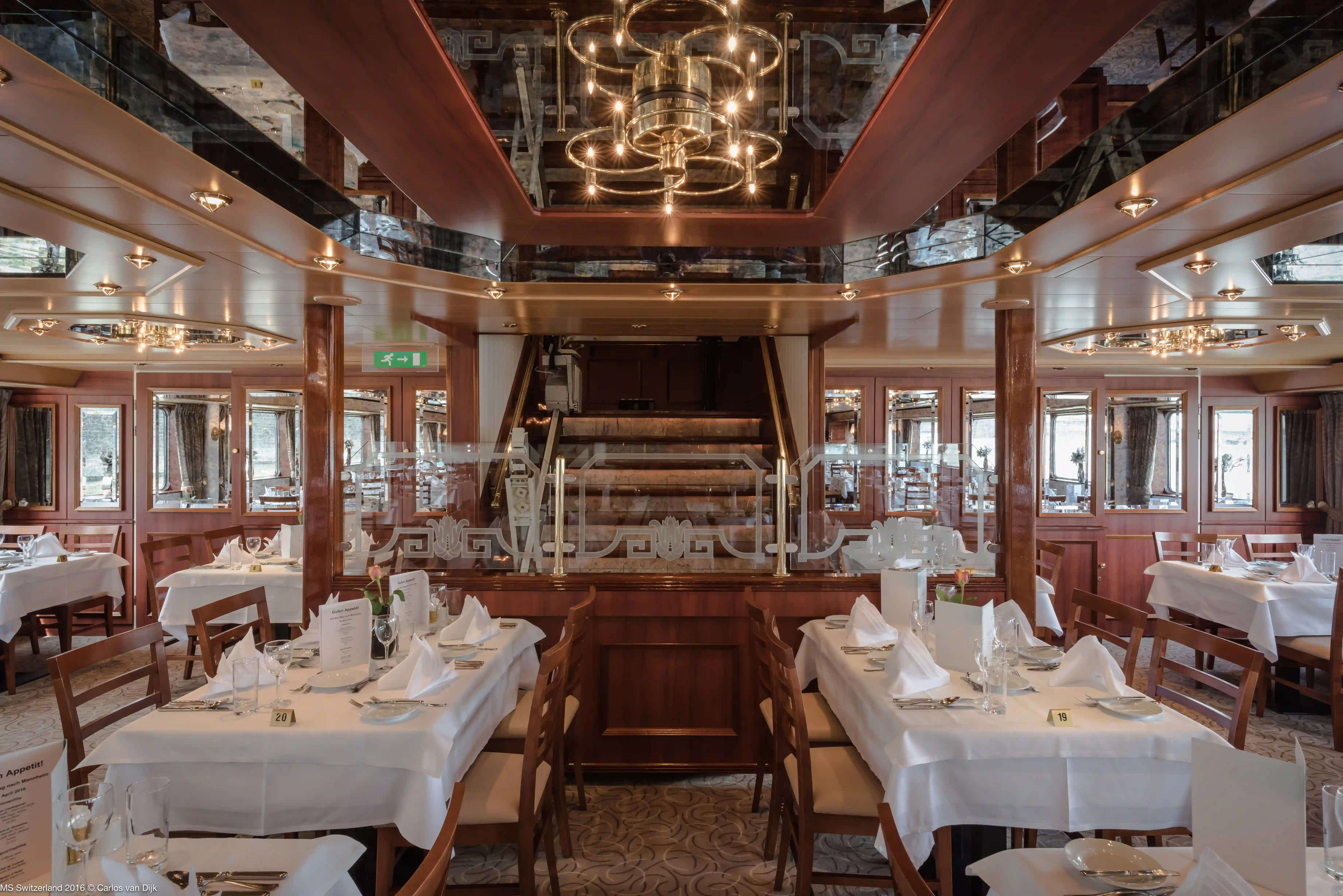 Blick in das stilvolle Schiffsrestaurant mit weiss gedeckten Tischen, Holzstühlen und grossen Fenstern mit Blick nach draussen.