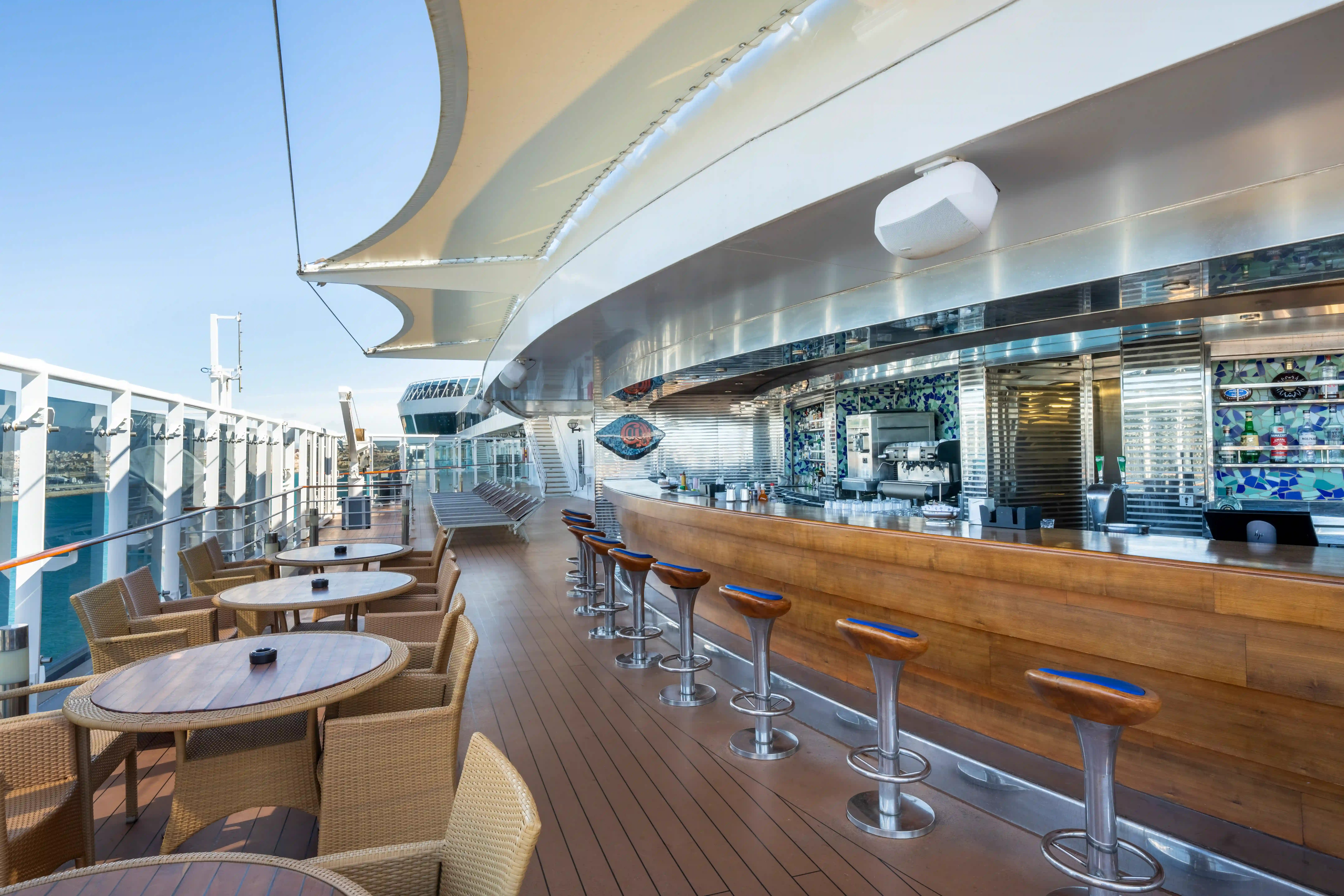 Aussenbar auf der MSC Fantasia mit Barhockern, Sitzgruppen und Blick auf das Meer.