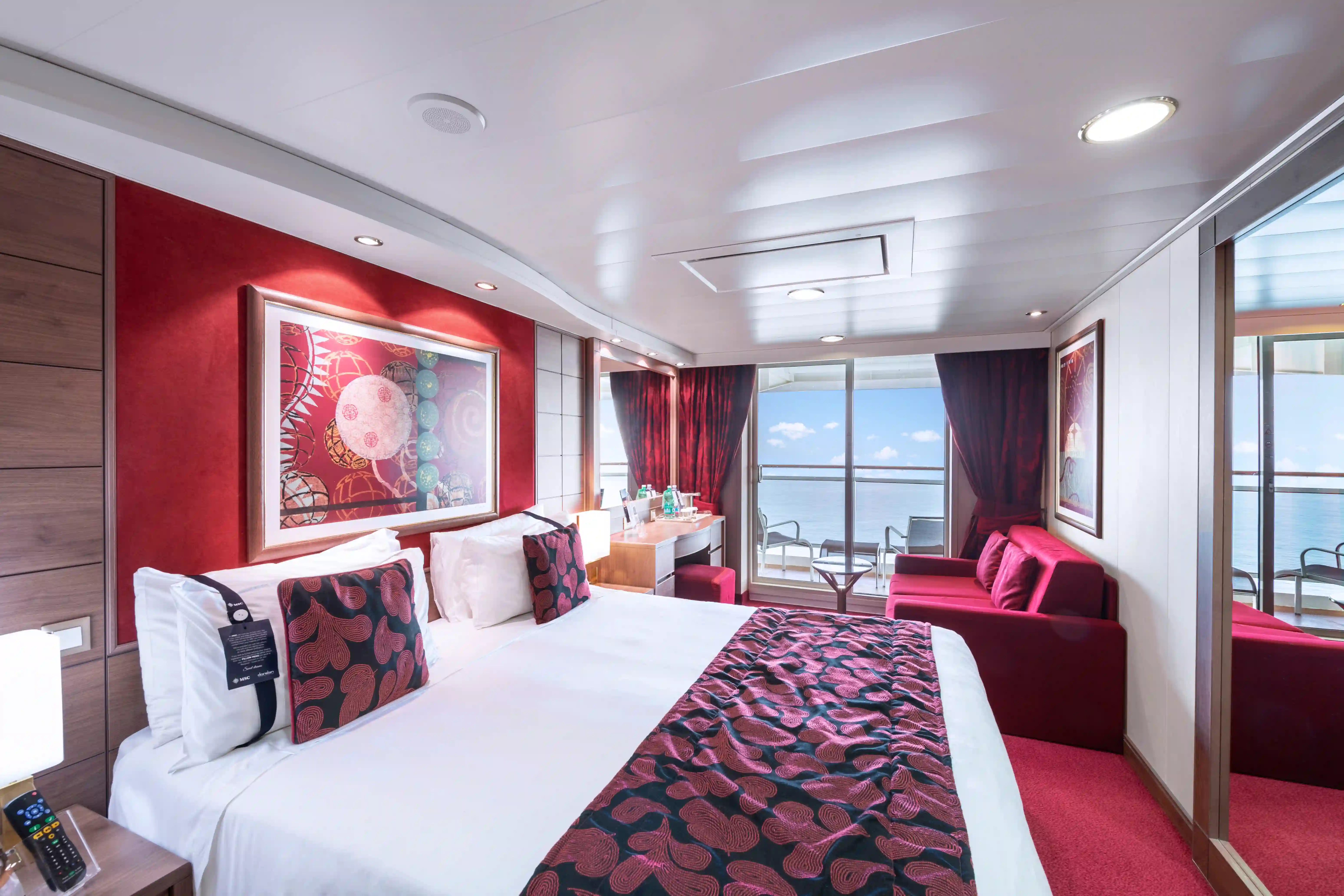 Geräumige Balkonkabine der MSC Magnifica mit Doppelbett, Schreibtisch, Sitzbereich und grossen Glastueren zum Balkon.