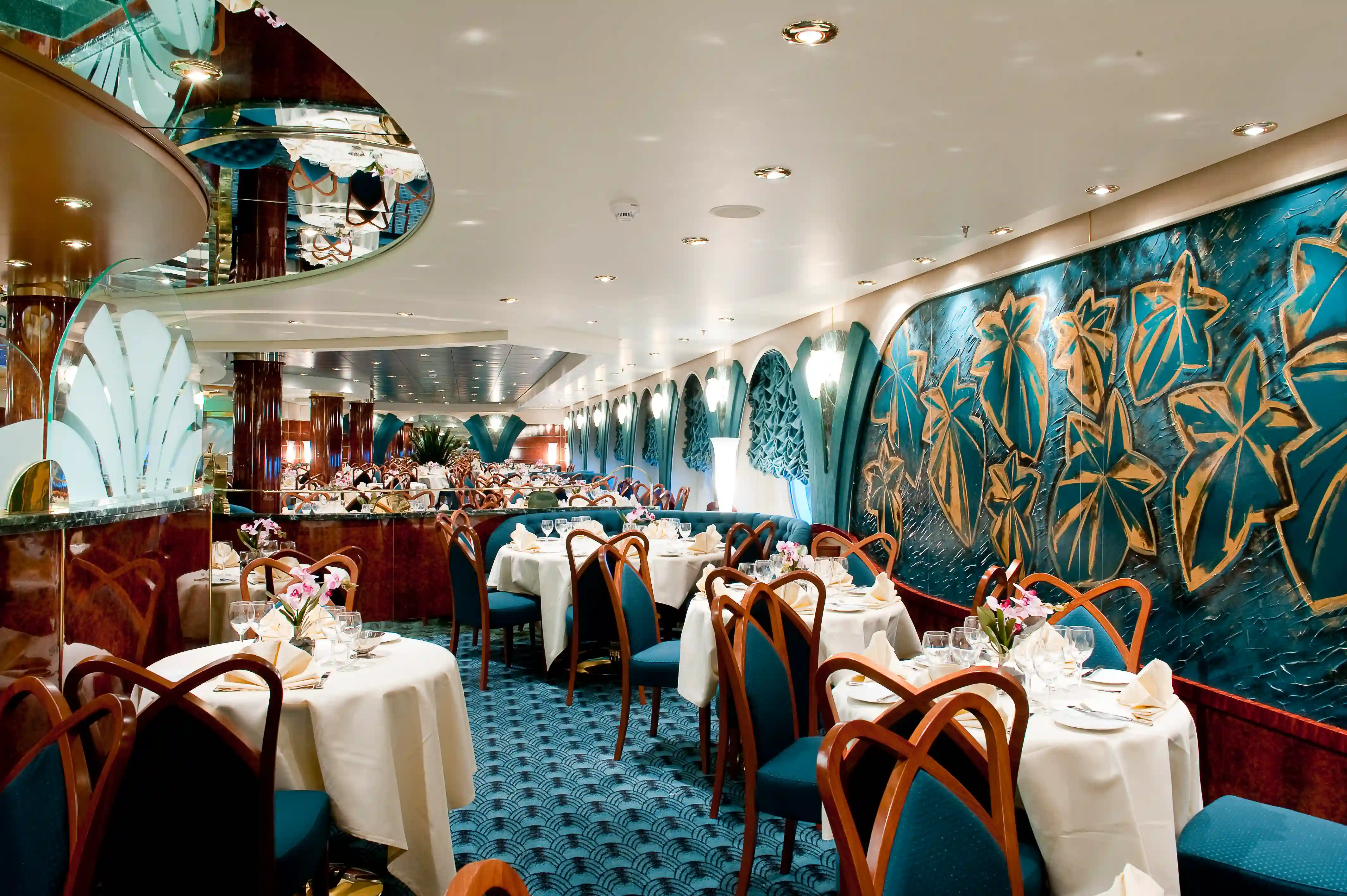 Elegantes Restaurant auf der MSC Magnifica mit gedeckten Tischen, gepolsterten Stuehlen und dekorativen Wandmotiven.
