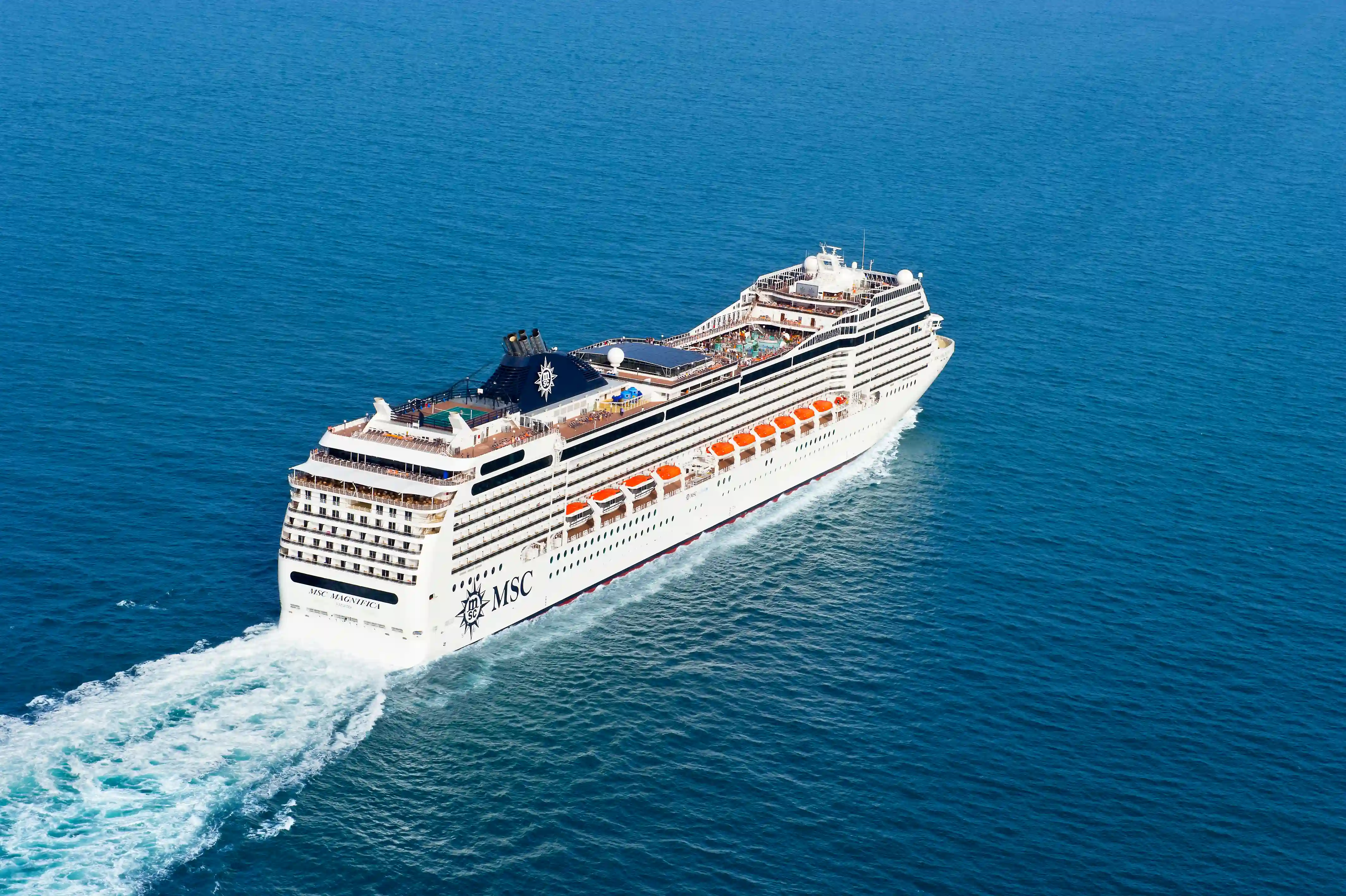 MSC Magnifica faehrt auf blauem Meer, aus erhöhter Perspektive fotografiert, mit sichtbaren Decks und Poolbereichen.