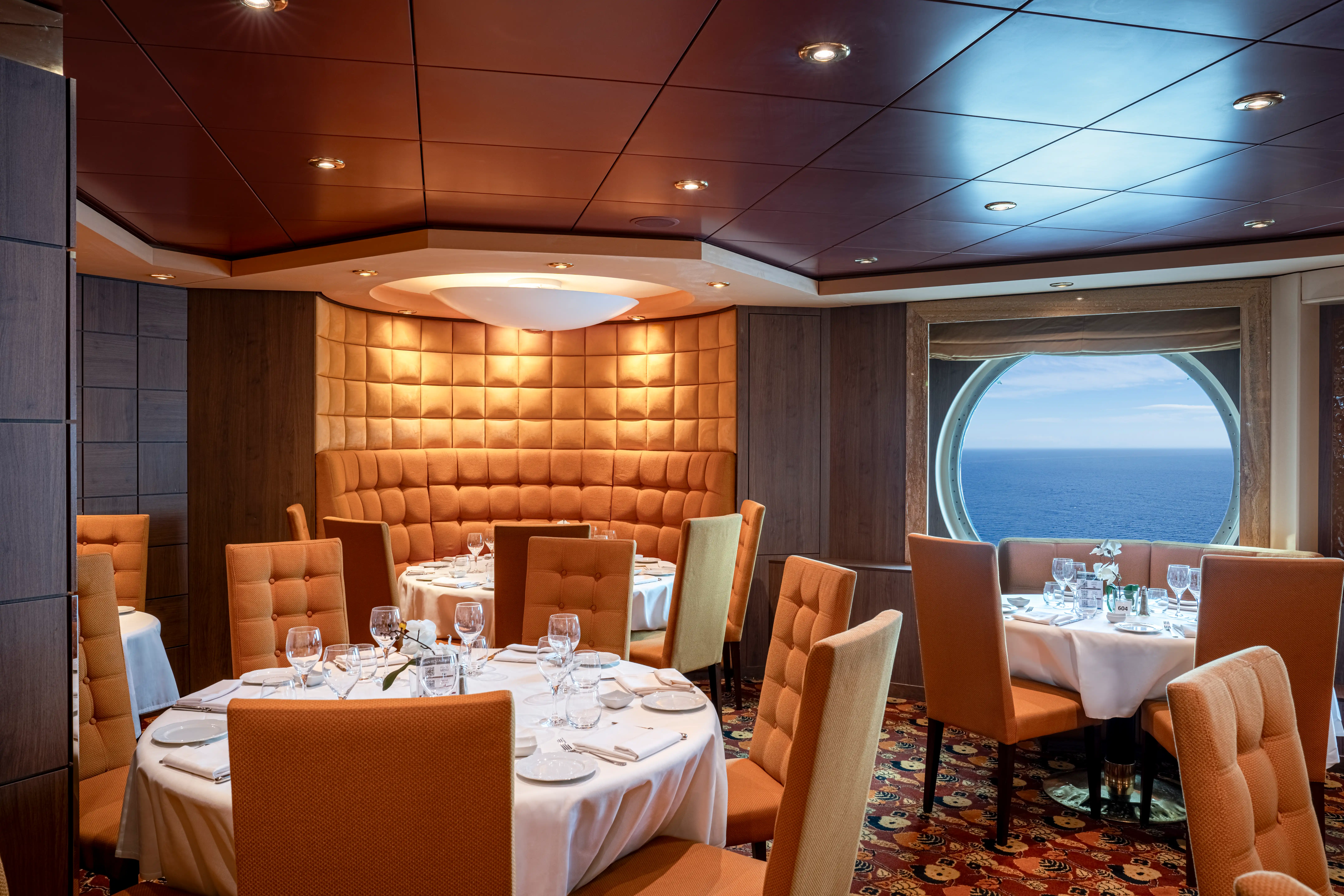 Restaurant avec tables dressées, chaises rembourrées et vue sur la mer