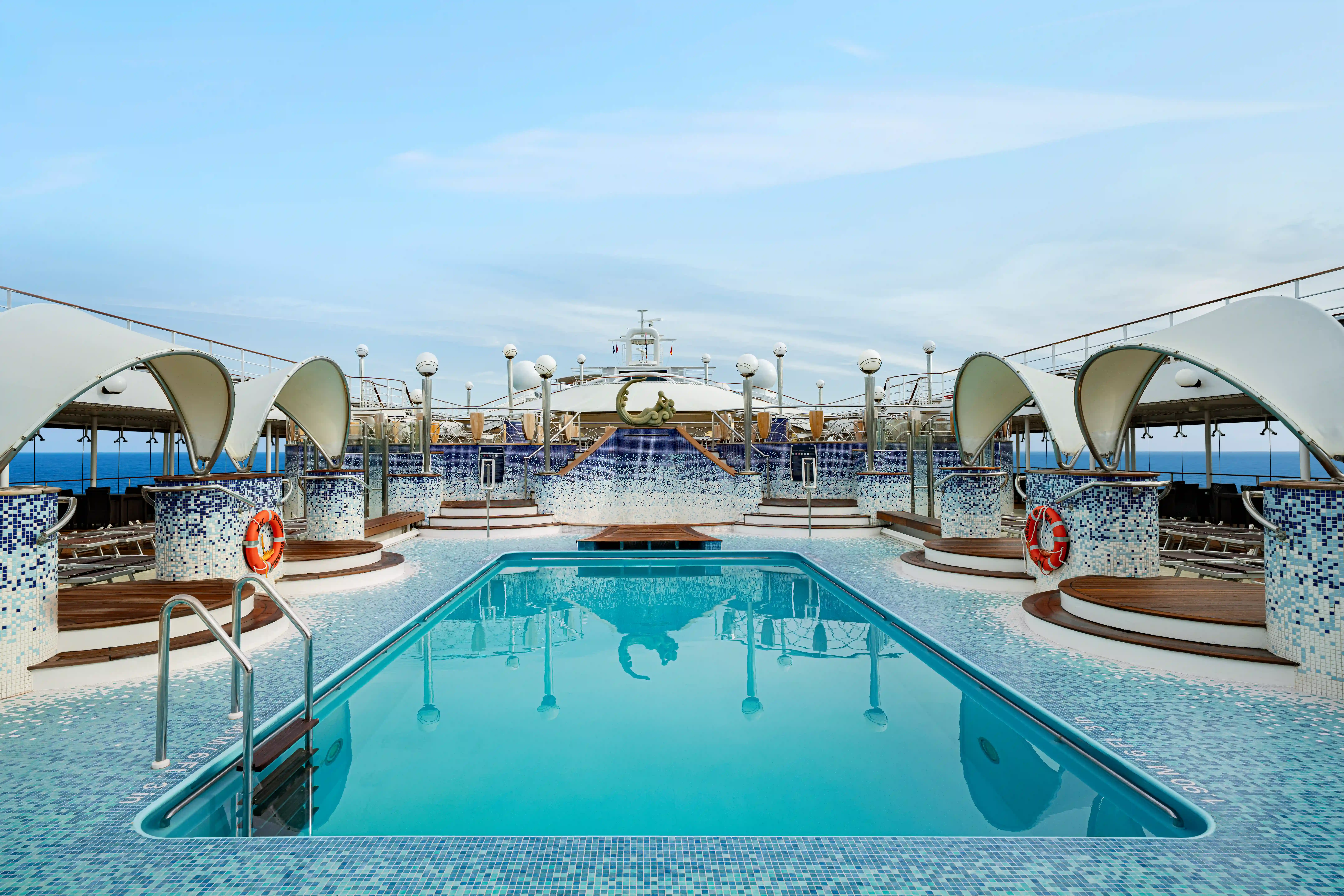 Aussenpool auf der MSC Poesia mit Liegebereichen, Mosaikfliesen und Blick auf das offene Meer
