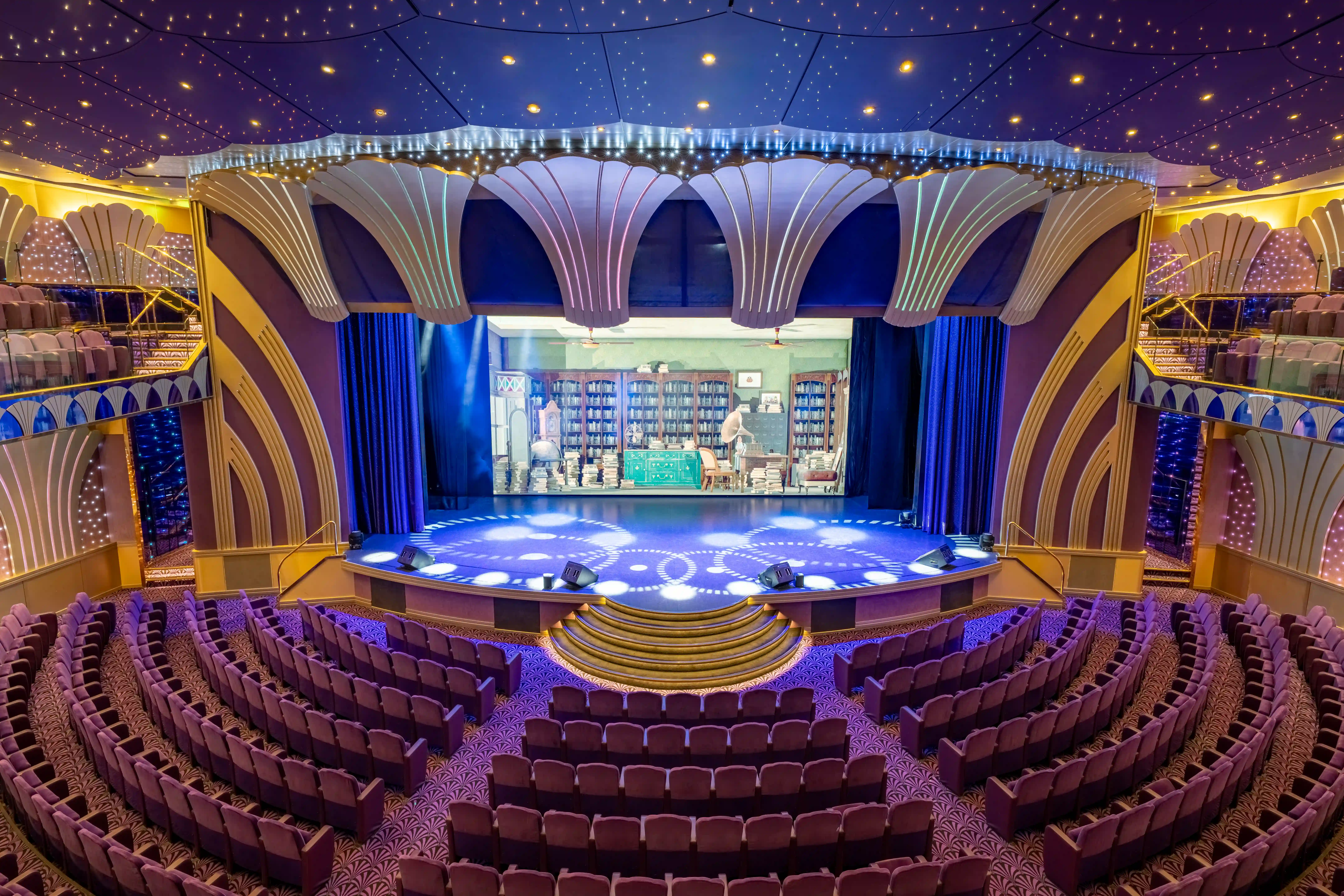 Grosses Theater auf der MSC Poesia mit Bühne, Sitzreihen, dekorativer Decke und stimmungsvoller Beleuchtung