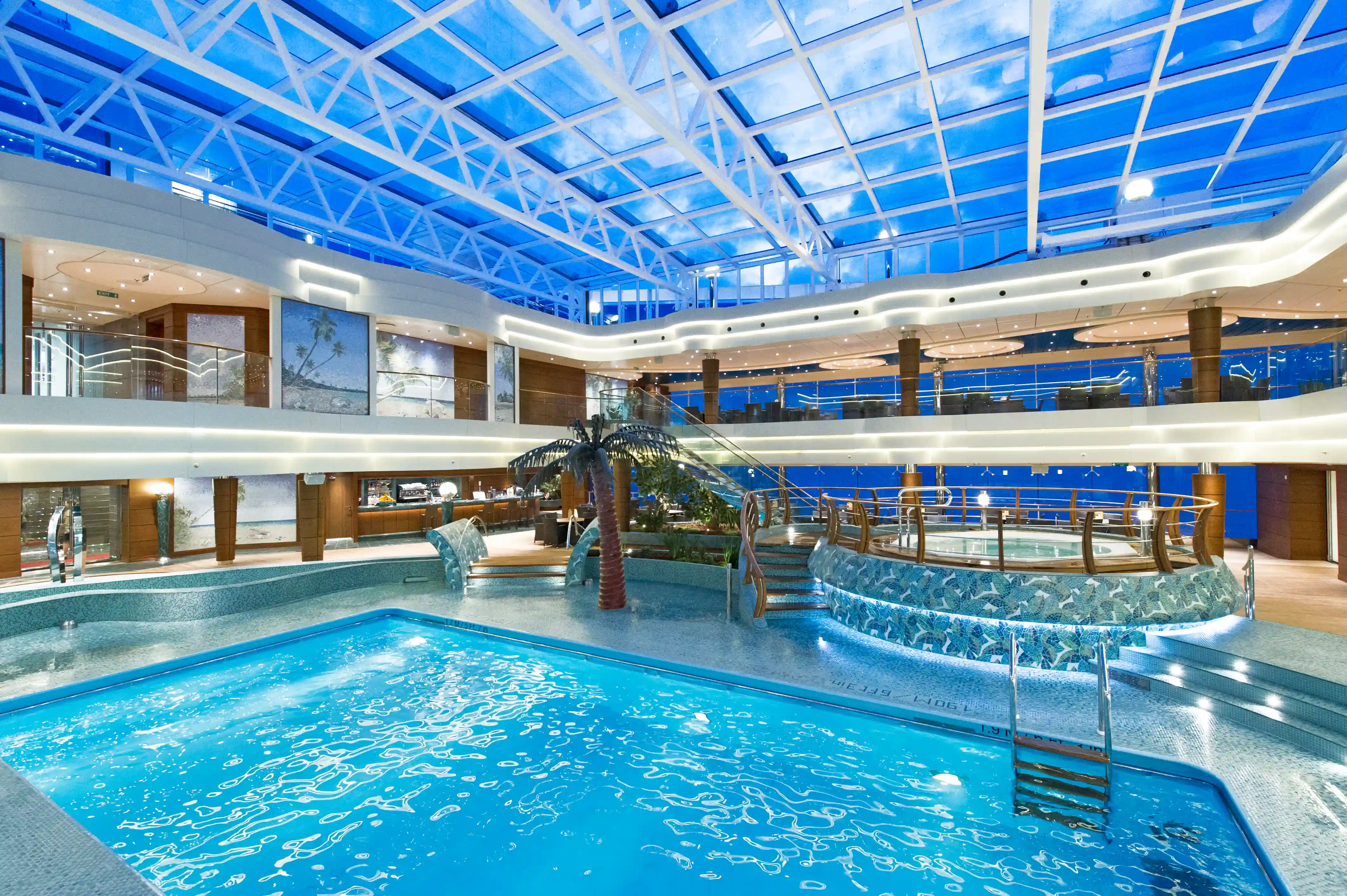 Beheizter Innenpool der MSC Preziosa mit Glasdach, Liegebereichen und Beleuchtung