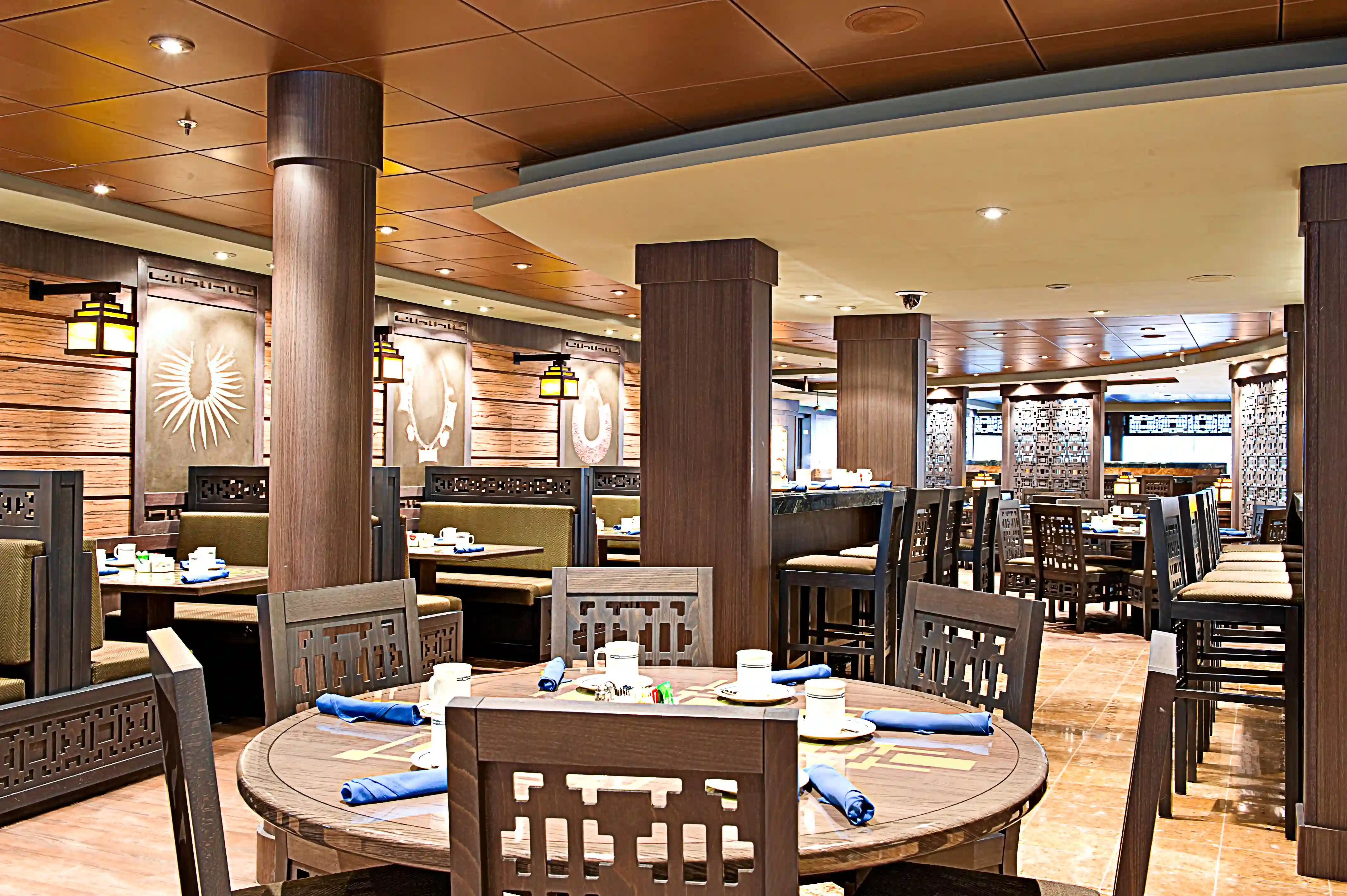 Restaurant der MSC Splendida mit runden Tischen, Sitzbaenken und warmem Licht