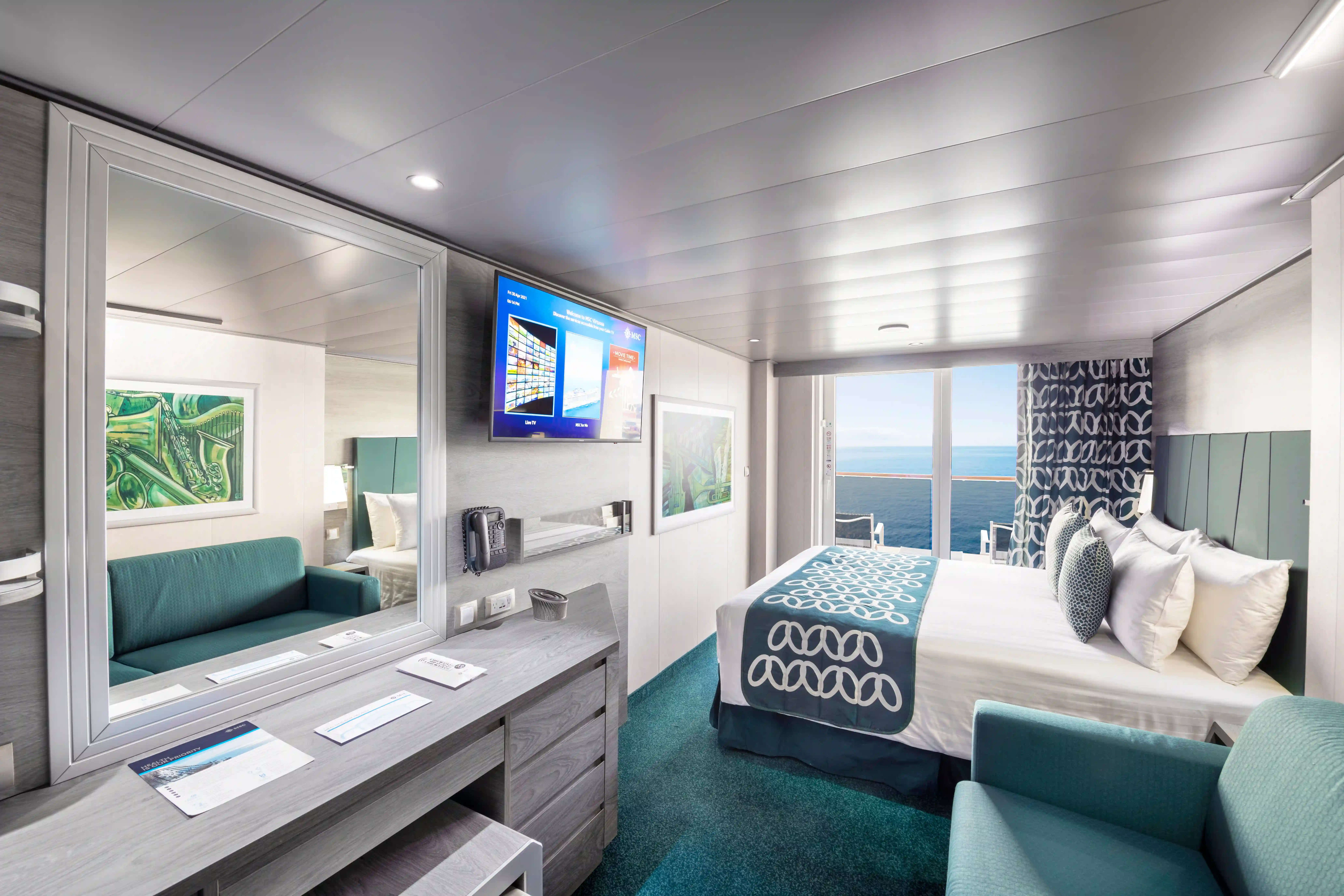 Balkonkabine auf der MSC Virtuosa mit Doppelbett, Schreibtisch, Sitzmöbeln und Zugang zum Balkon