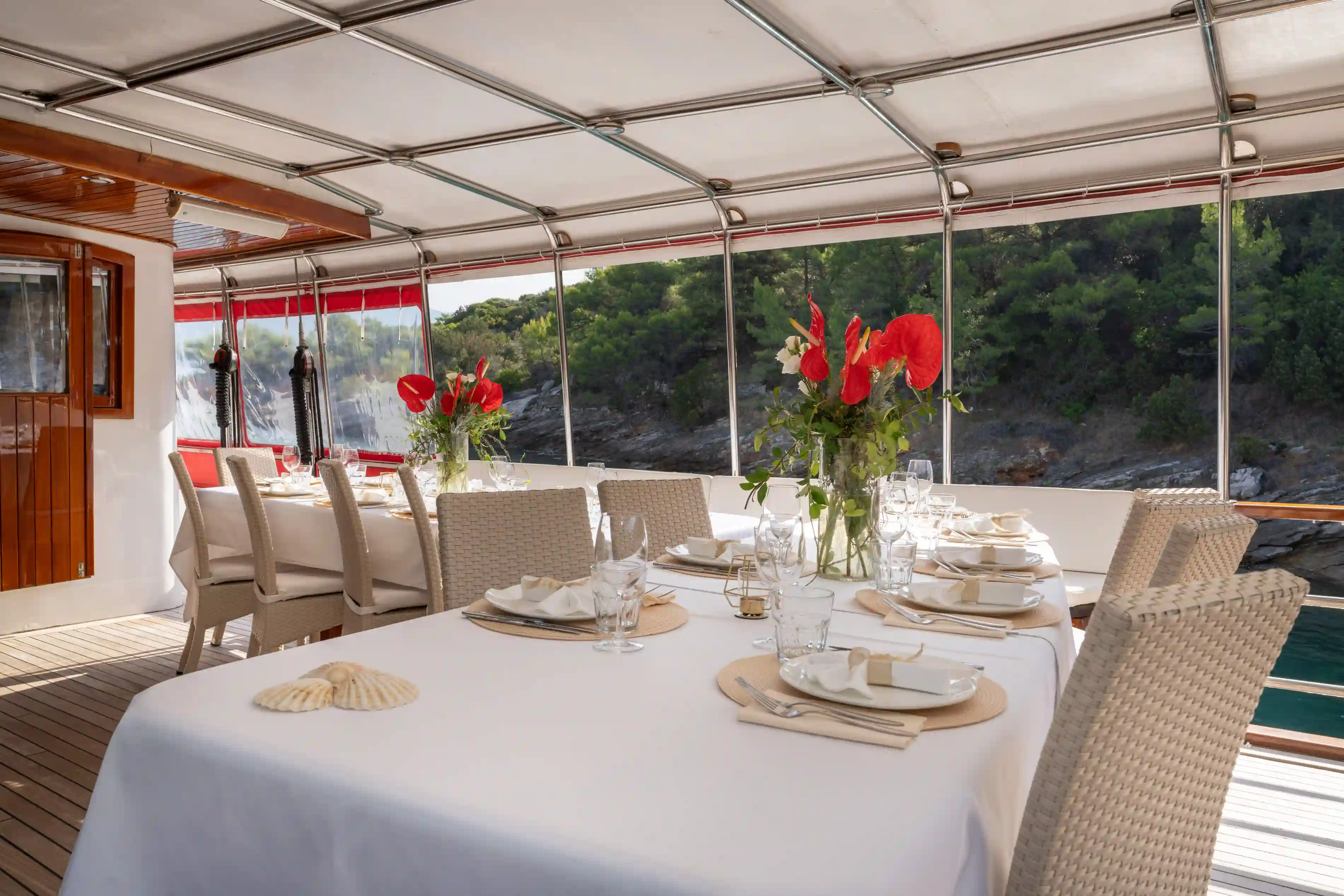 Espace restaurant couvert a bord avec tables dressées et vue sur la côte