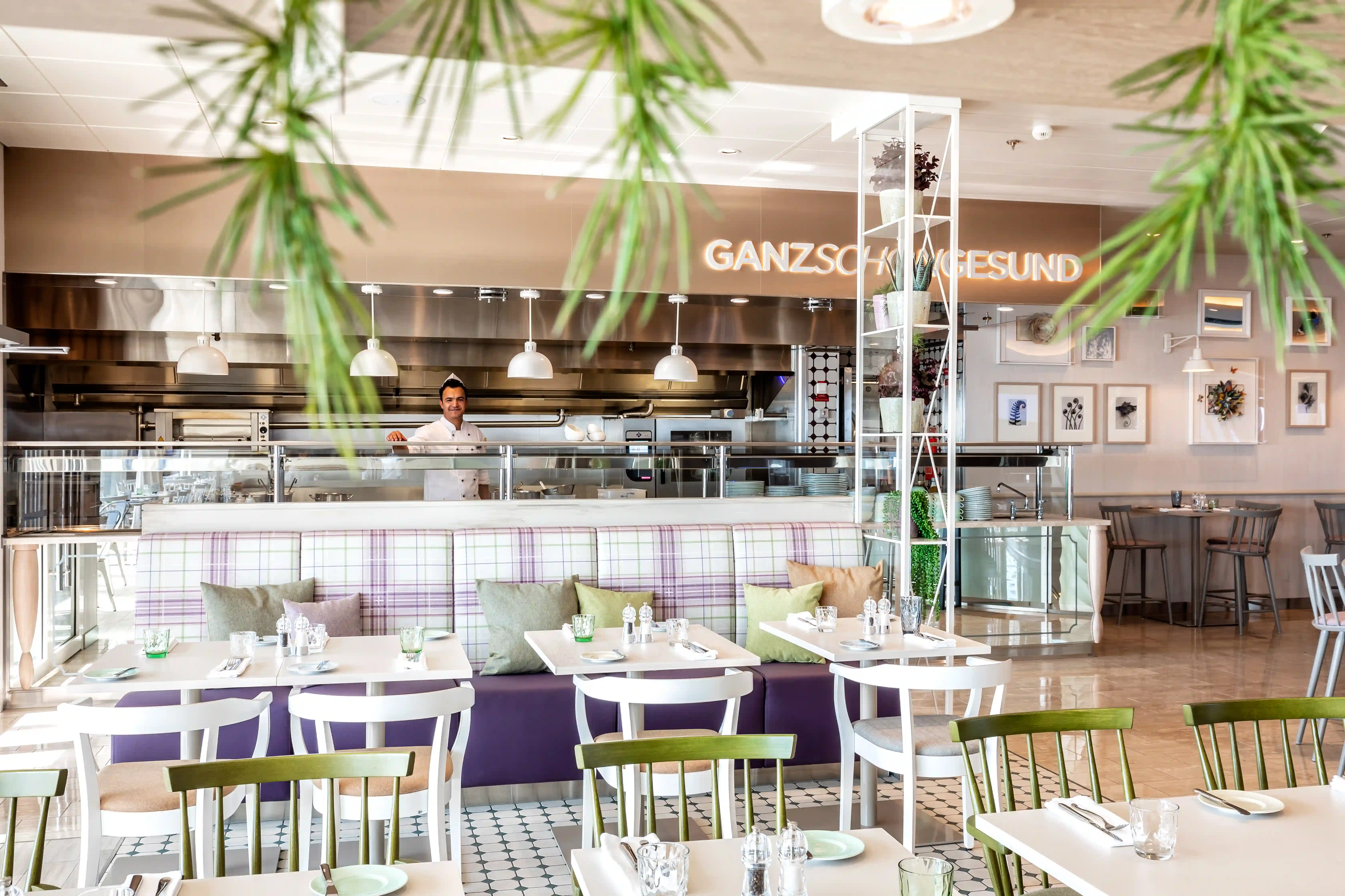 Modernes Bistro mit offenen Sitzbereichen, gedeckten Tischen und offener Küche