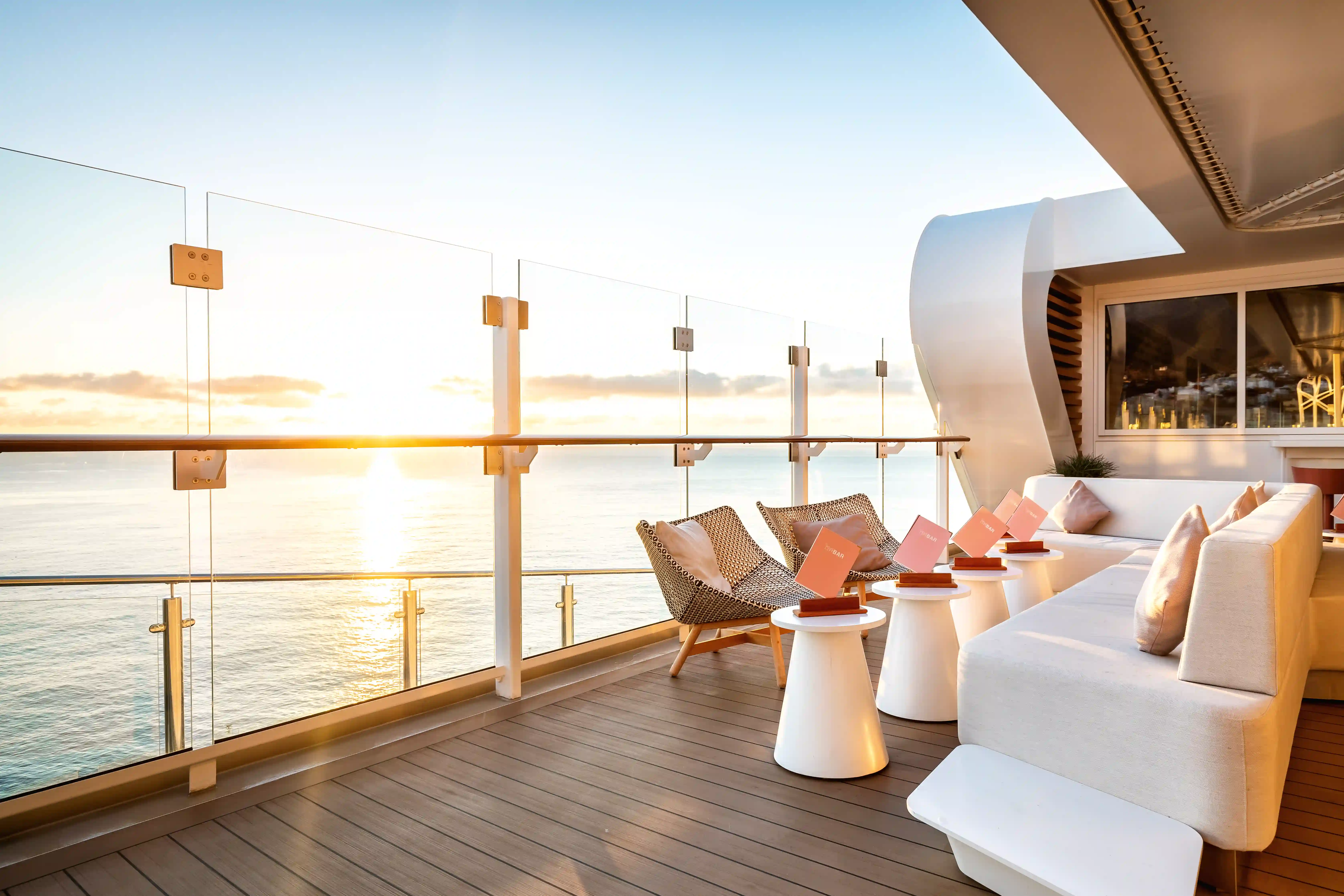 Lounge Terrasse mit Sesseln, Beistelltischen und Meerblick bei Sonnenuntergang