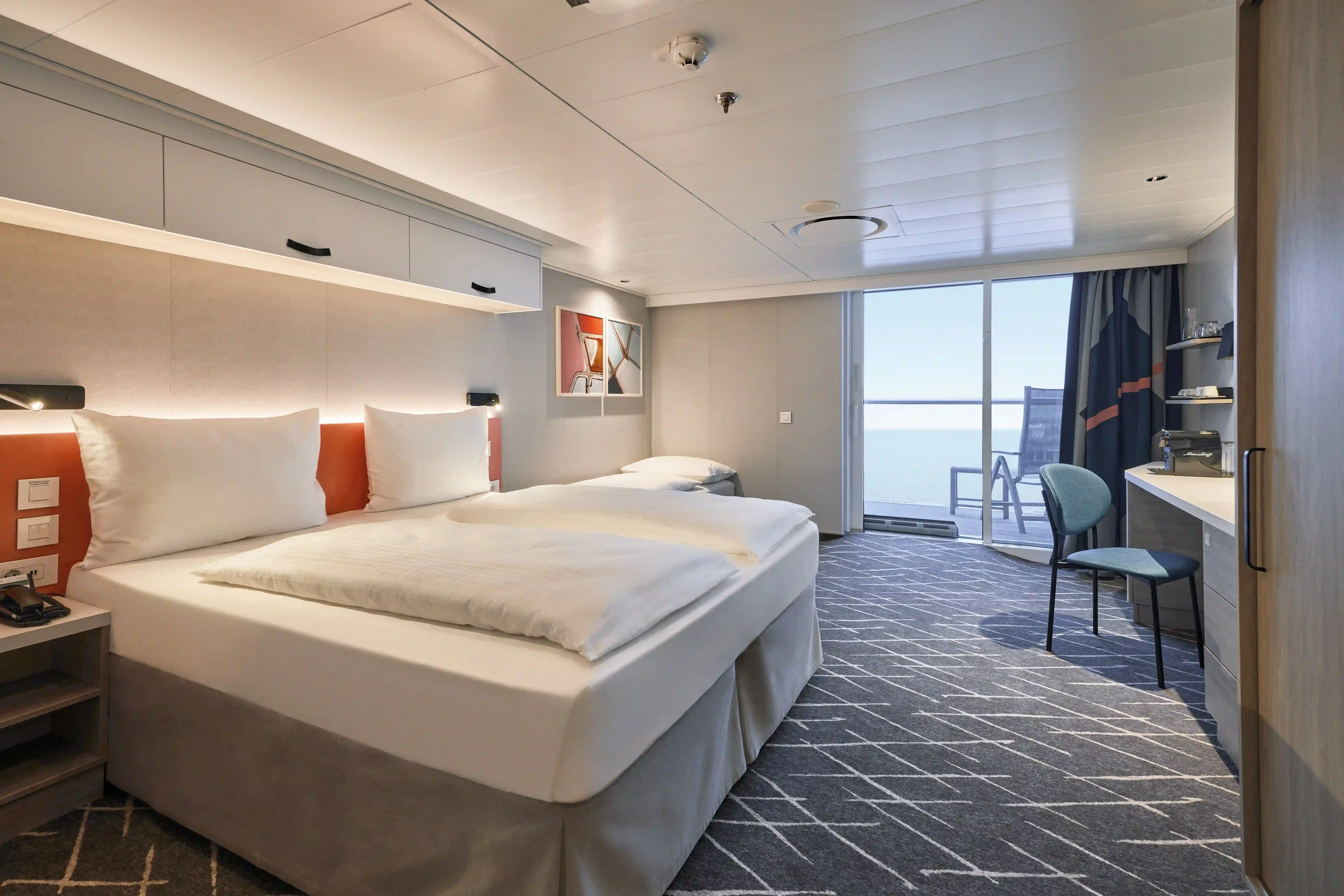 Balkonkabine mit Doppelbett, Sitzbereich und Zugang zum Balkon mit Meerblick