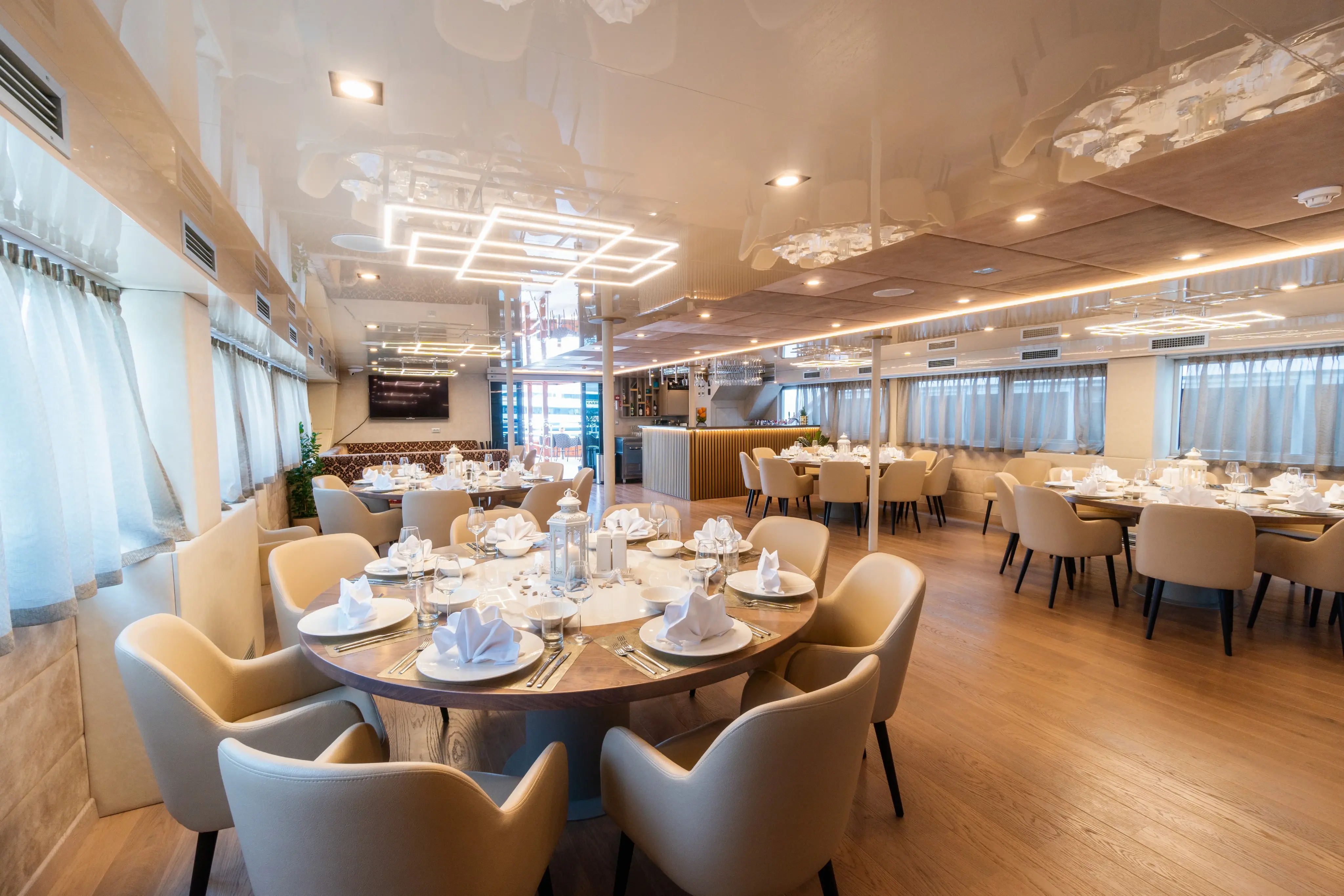 Restaurant elegant du MS Adriatic Sky avec des tables rondes dressees, des fauteuils confortables et de grandes fenetres.