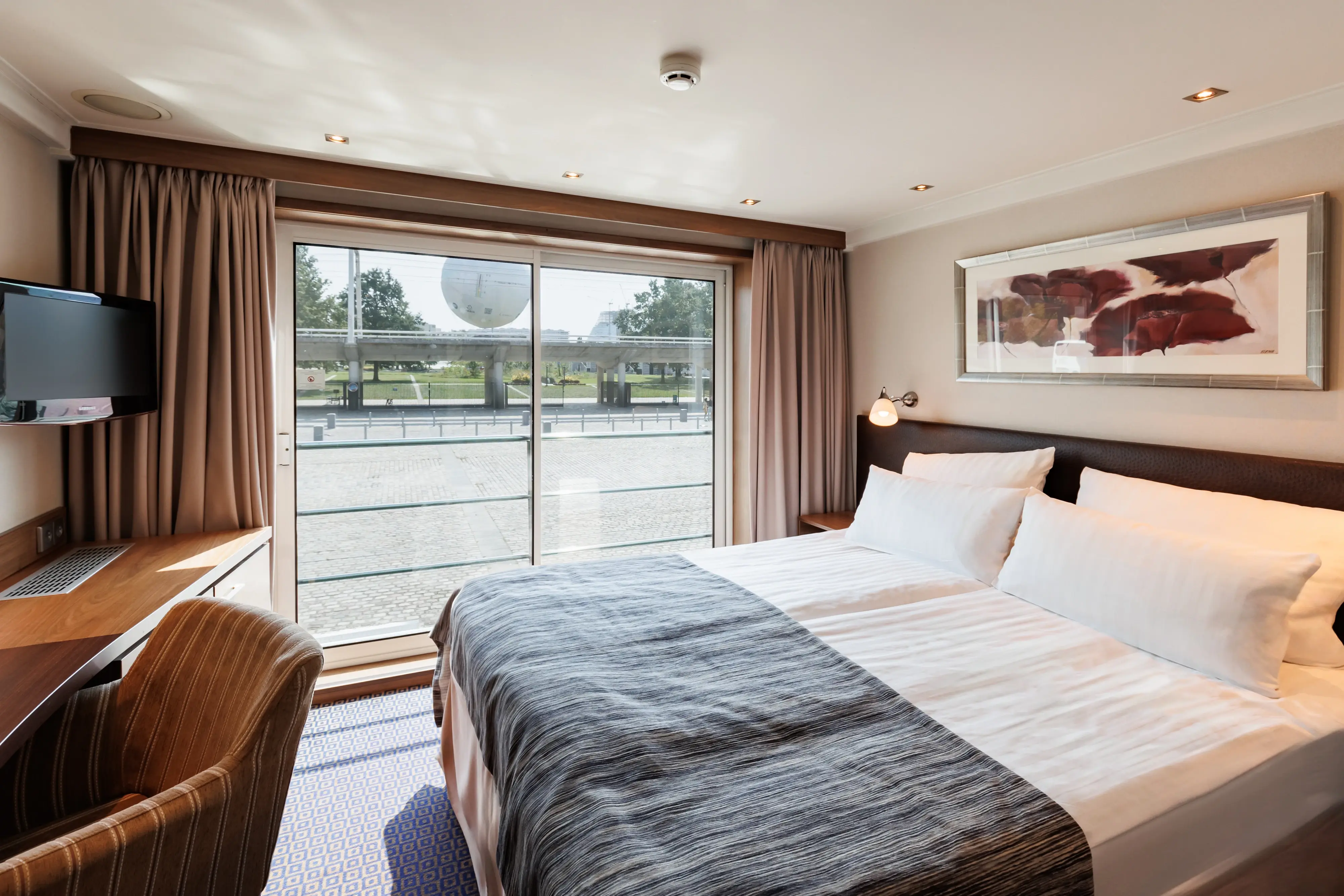 Cabine lumineuse du MS Monarch Countess avec lit double, bureau et grande fenetre.