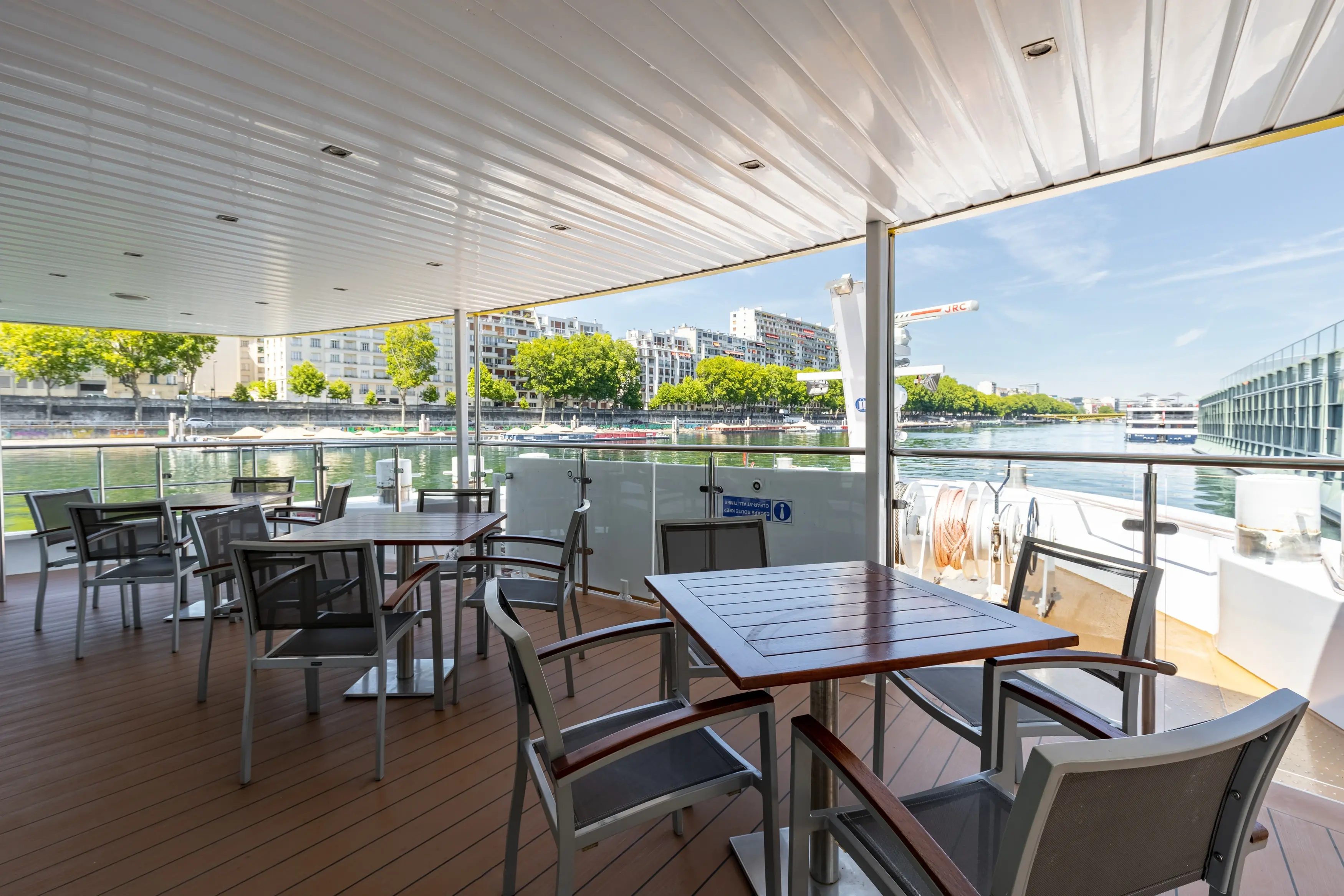 Espace exterieur couvert du MS Monarch Countess avec places assises et vue sur les rives du fleuve.