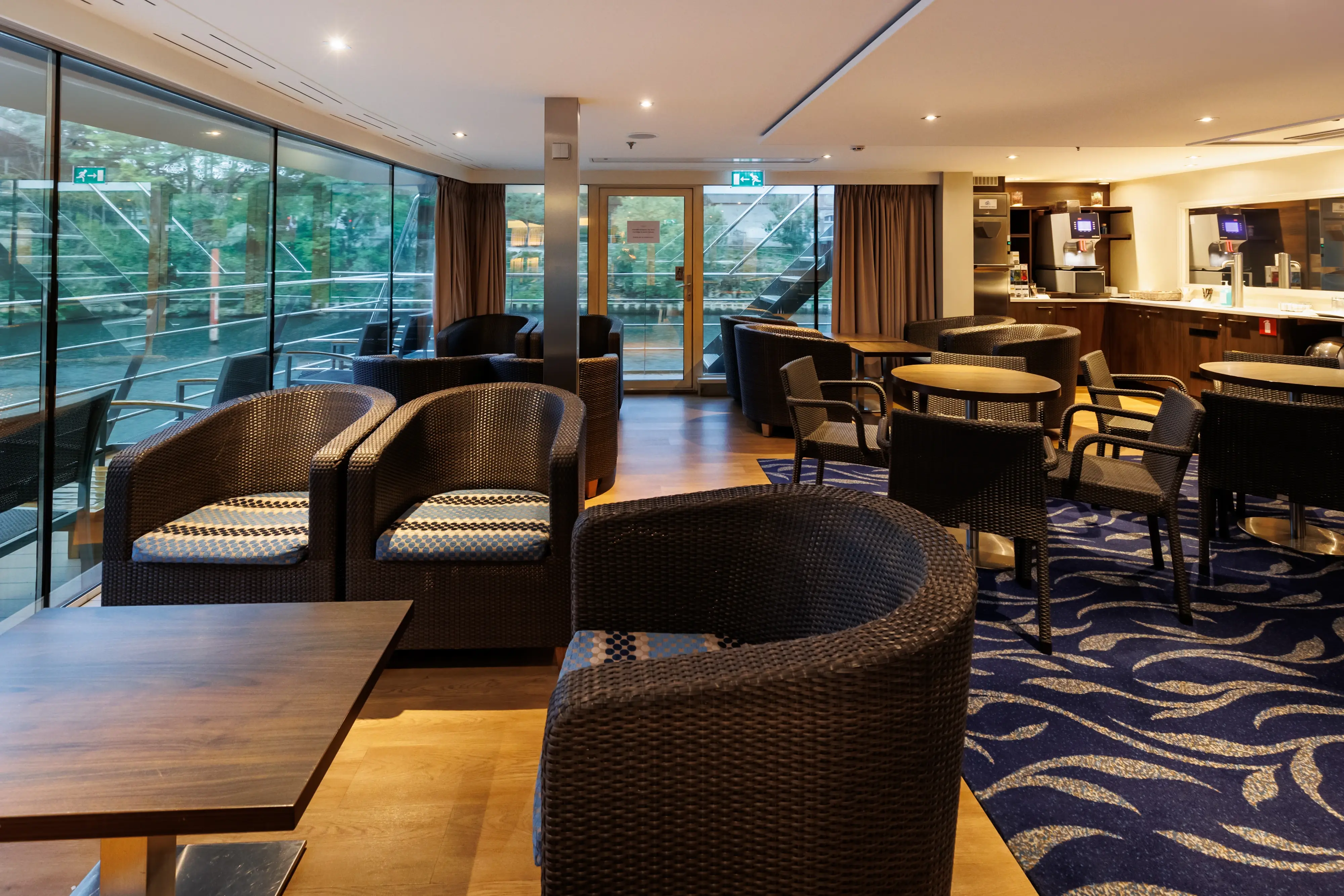 Salon confortable du MS Monarch Countess avec fauteuils, tables et baies vitrees donnant sur le fleuve.